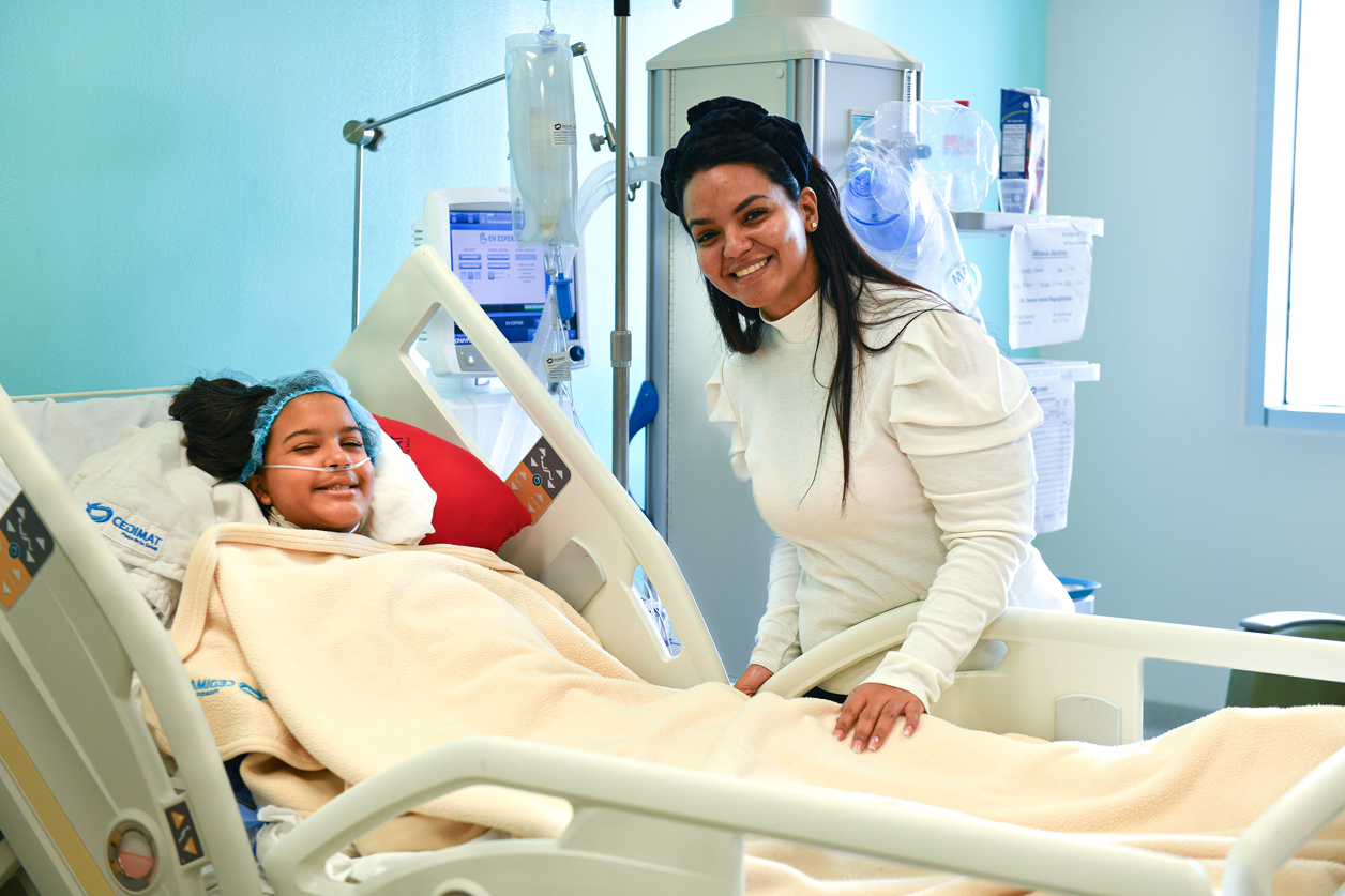 12-year-old Miranda recovers from successful mitral valve repair surgery, with her mother at her bedside.