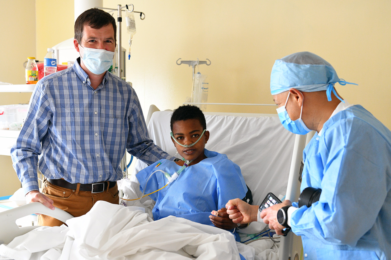 Owen Robinson, Executive Director of Haiti Cardiac Alliance, and Dr. Ricardo Lazala, the Director of Latin American Relations at the Mitral Foundation, check in on 17-year-old Emmanuel after surgery.